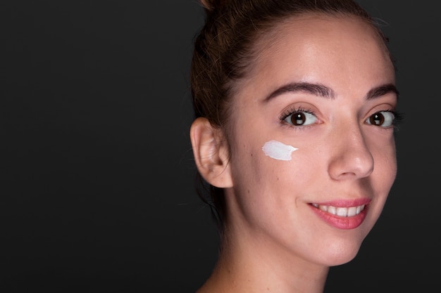 Young woman using moisturizer 