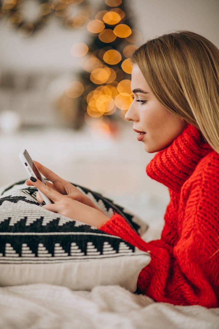 Free Photo young woman using phone on christmas