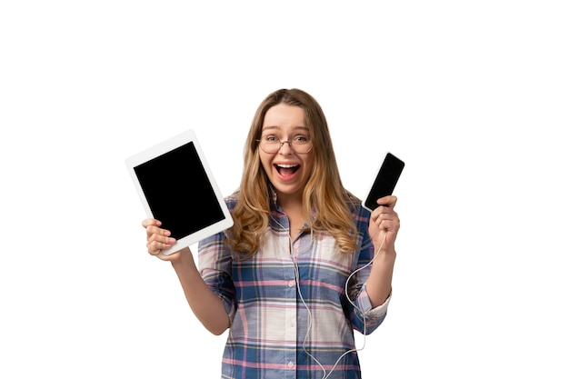 Молодая женщина, использующая смартфон, устройства, гаджеты, изолированные на белой стене студии