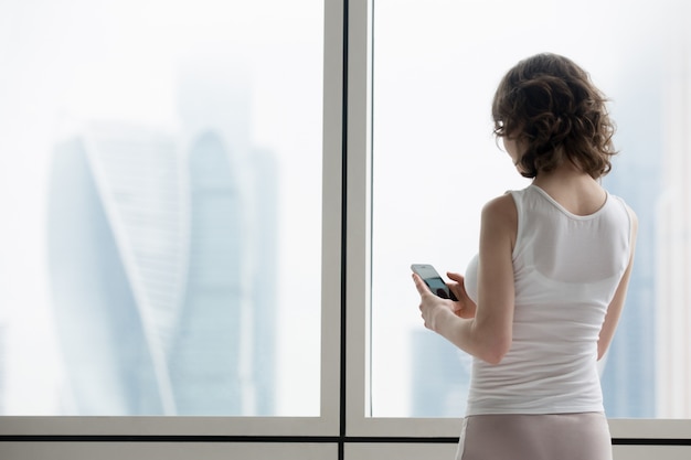 Free photo young woman using smartphone indoors