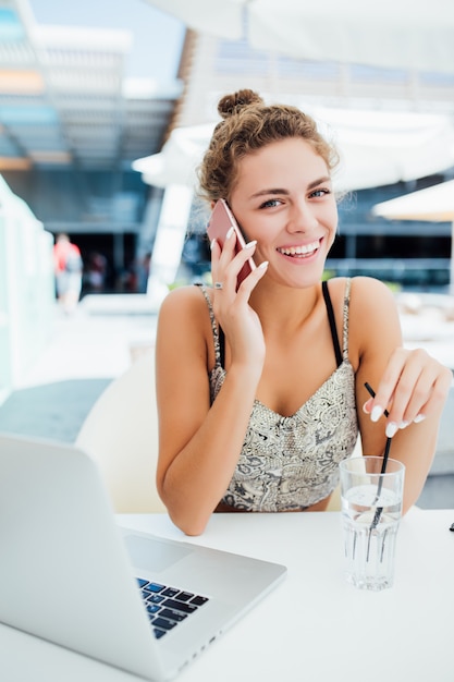 屋外のコーヒーショップでスマートフォンを使用して若い女性。