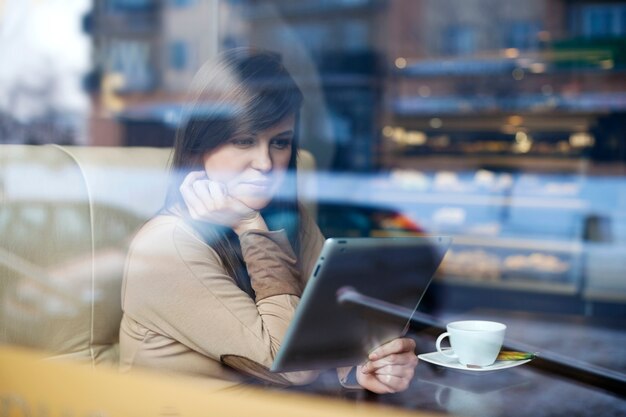 コーヒーショップでタブレットを使用して若い女性