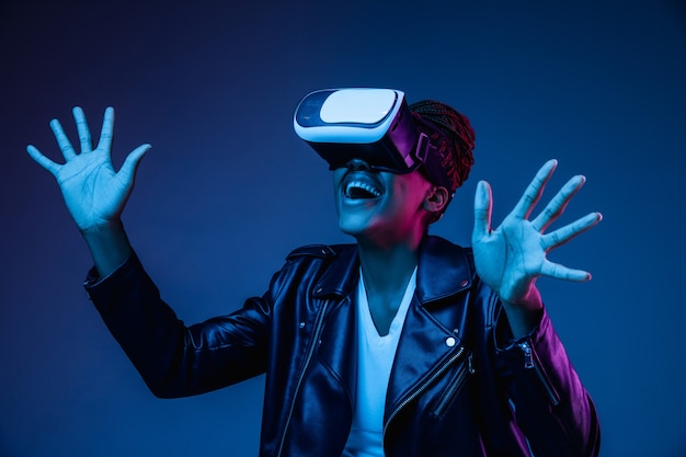 Young woman using VR glasses in neon light