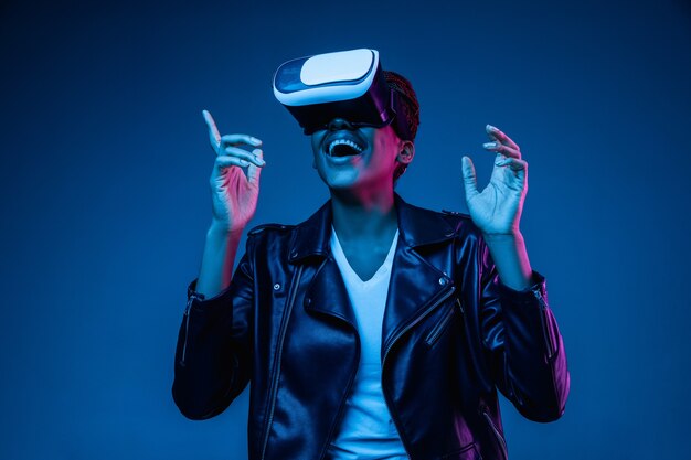 Young woman using VR glasses in neon light