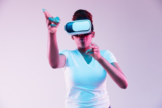 네온 불빛에 VR 안경을 사용하는 젊은 여자