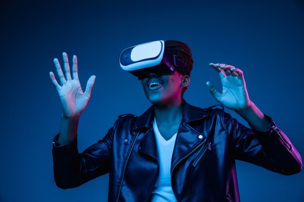 Young woman using VR-glasses with neon lights