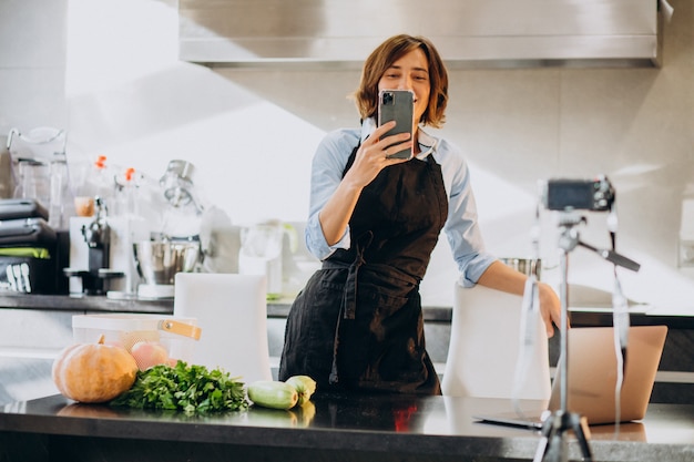 Young woman videoblogger cooking at the kitchen and filming