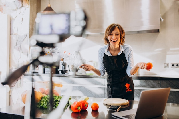 Видеоблогер молодой женщины готовит на кухне и снимает