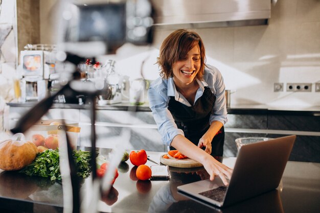 Young woman videoblogger cooking at the kitchen and filming