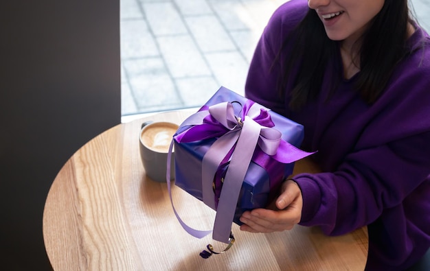 A young woman in violet sweater with purple gift box