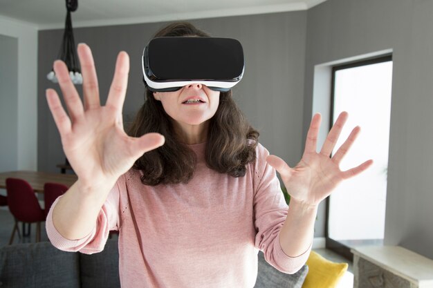 Young woman in virtual reality goggles playing online game