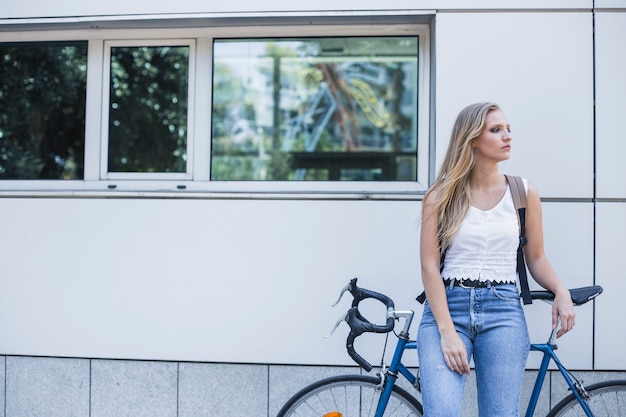 Foto gratuita giovane donna in attesa di qualcuno con la bicicletta