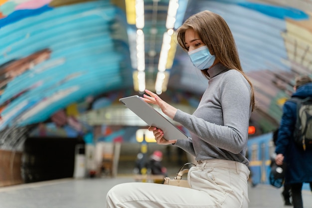 タブレットで地下鉄の駅で待っている若い女性