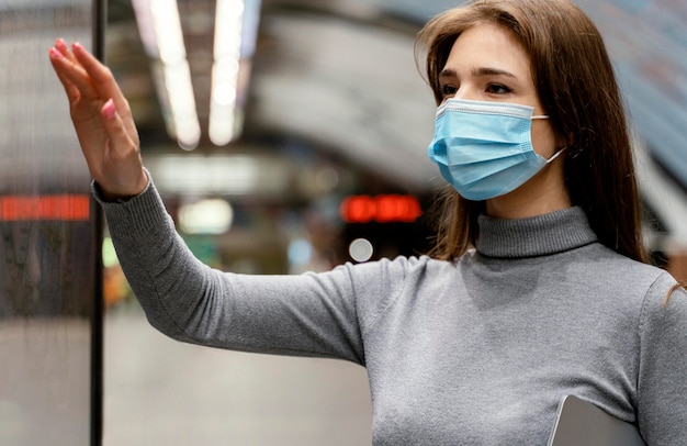 Foto gratuita giovane donna in attesa in una stazione della metropolitana con un tablet