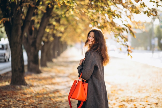 Молодая женщина гуляя в парк осени