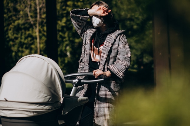 Young woman walking in protection mask with baby carriage