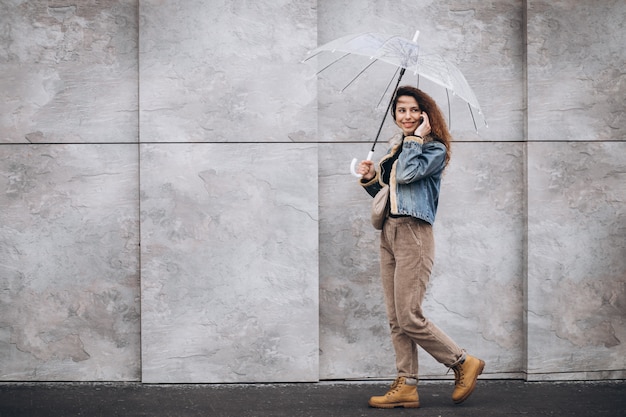 Free photo young woman walking in the rain with umbrella