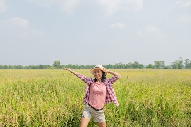 태국에서 쌀 필드에 걷는 젊은 여성. 지구의 깨끗한 곳을 여행하고 자연의 아름다움을 발견합니다. 모자 서와 젊은 여성 여행자입니다.