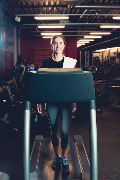 Young woman walking on treadmill at gym