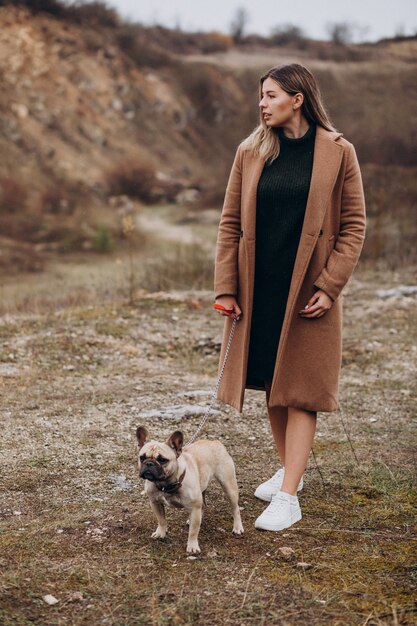 Young woman walking with bulldog pet in park