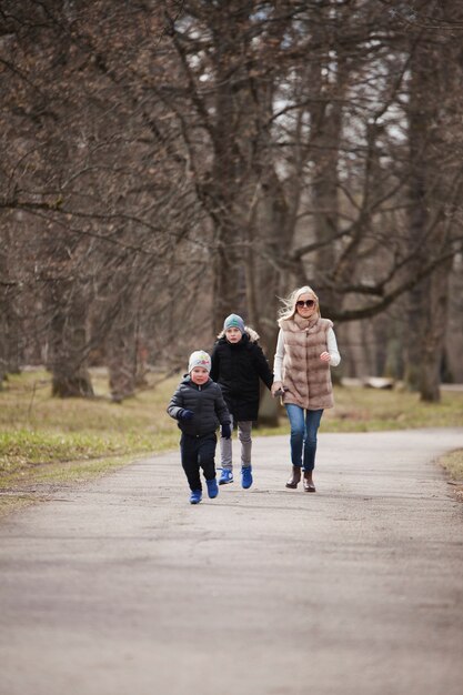 젊은 여자는 공원에서 그녀의 아이들과 함께 산책