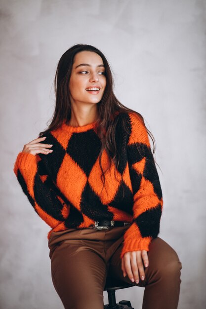 Young woman in warm sweater sitting on chair