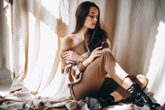 Free photo young woman in a warm sweater sitting on ground