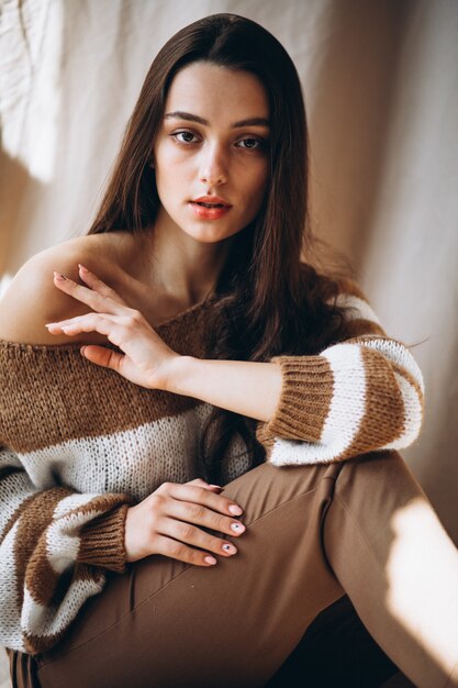 Young woman in a warm sweater sitting on ground