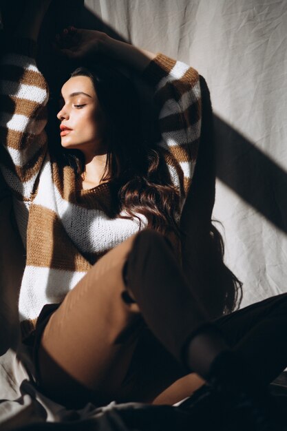 Young woman in a warm sweater sitting on ground