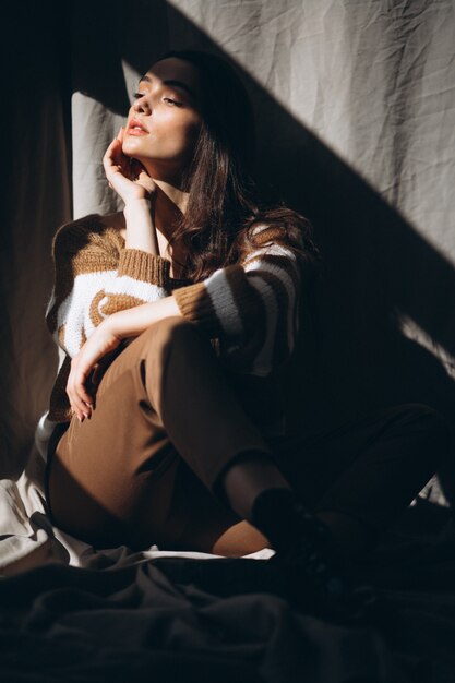 Free photo young woman in a warm sweater sitting on ground