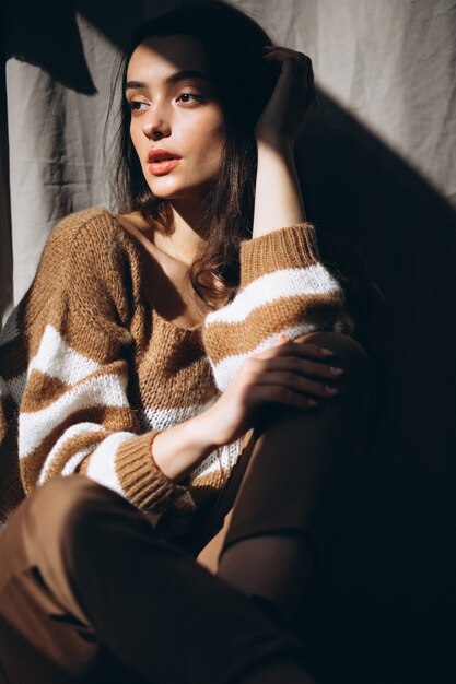 Free photo young woman in a warm sweater sitting on ground