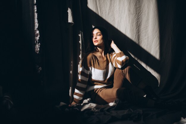 Young woman in a warm sweater sitting on ground