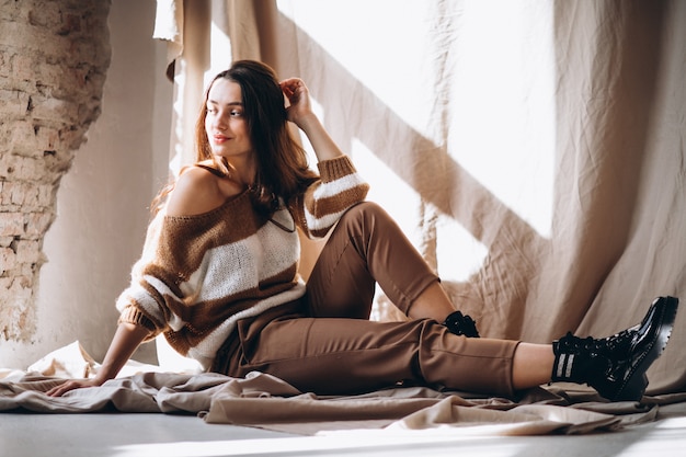 Young woman in a warm sweater sitting on ground