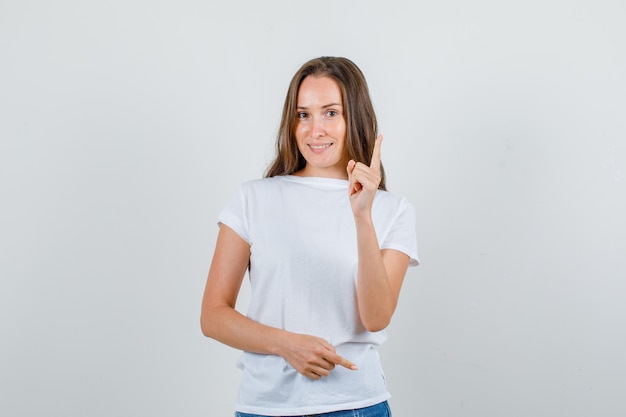 白いTシャツ、ショートパンツの正面図で指のジェスチャーで誰かに警告する若い女性。