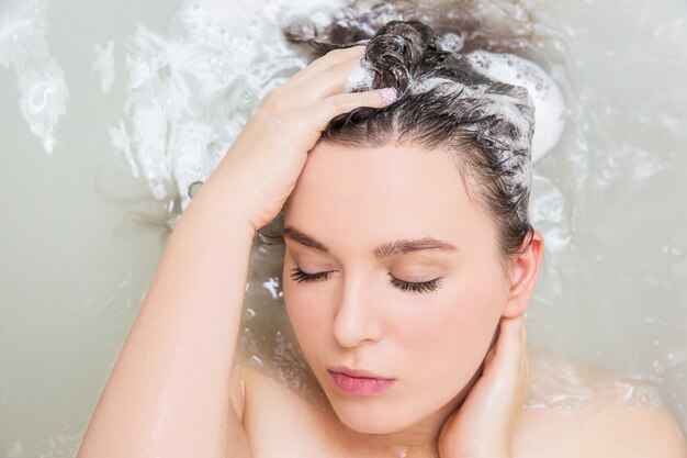 Premium Photo | Young woman washing hair. shampoo and foam on black woman's  hair.