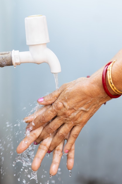 Young woman washing hands under the faucet