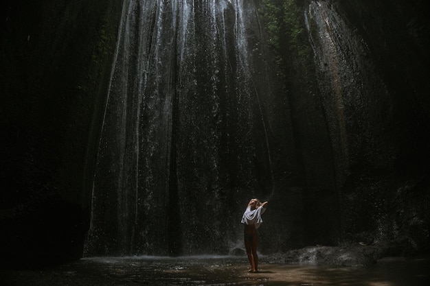 молодая женщина у водопада в скале Бали Индонезия
