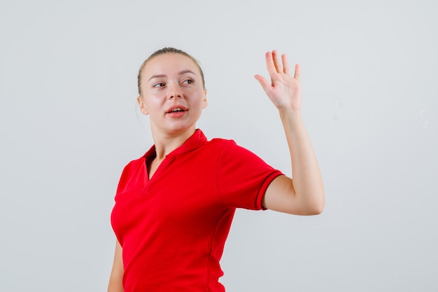 赤いTシャツを振り返り、陽気に見ながら手を振る若い女性