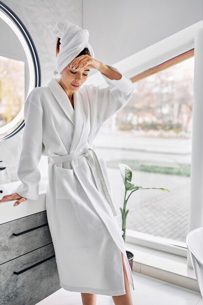 Young woman wearing a bathrobe and a towel on her hair