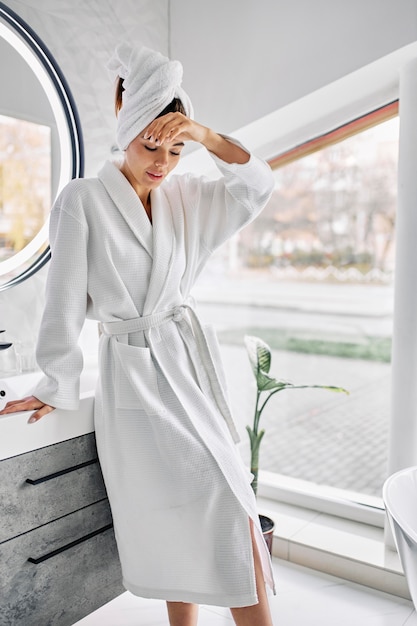 Young woman wearing a bathrobe and a towel on her hair