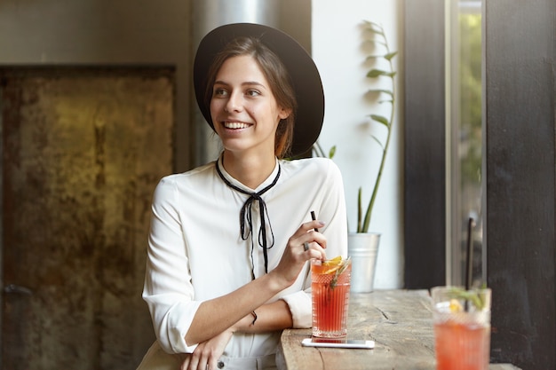 Young woman wearing big hat in cafe