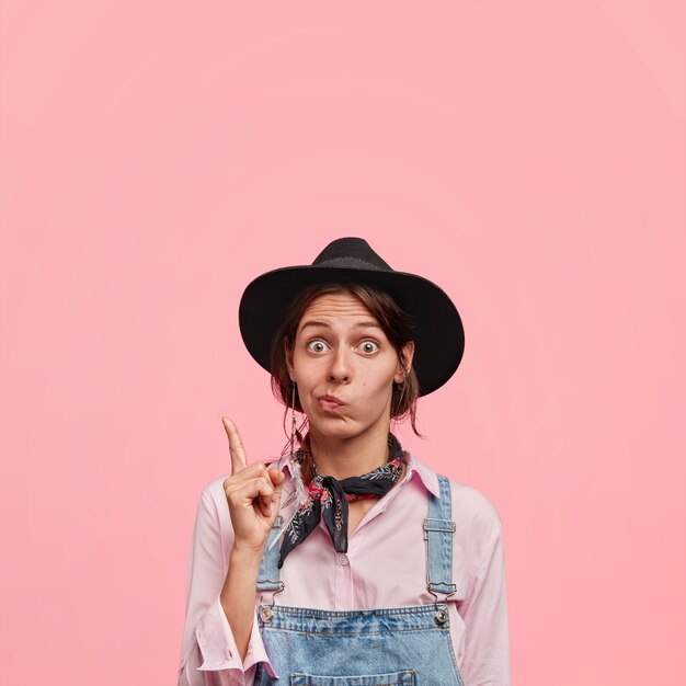 Young woman wearing big hat and denim overalls