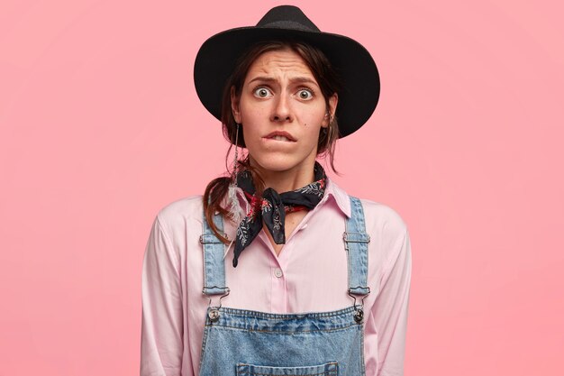 Young woman wearing big hat and denim overalls