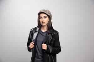 Бесплатное фото Молодая женщина в черной кожаной куртке и кепке.
