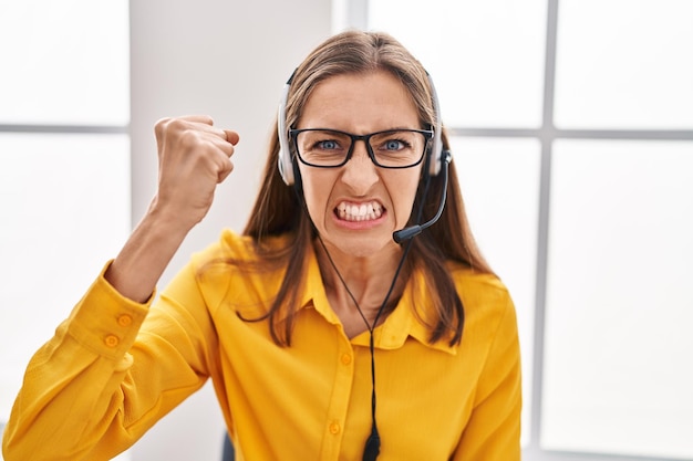 Young woman wearing call center agent headset annoyed and frustrated shouting with anger, yelling crazy with anger and hand raised
