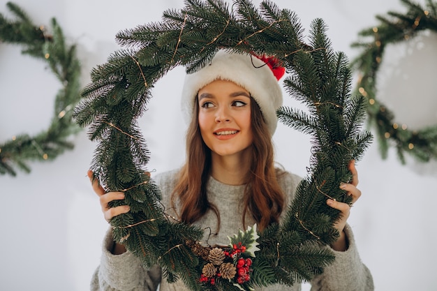 Free photo young woman wearing christmas hat on christmas