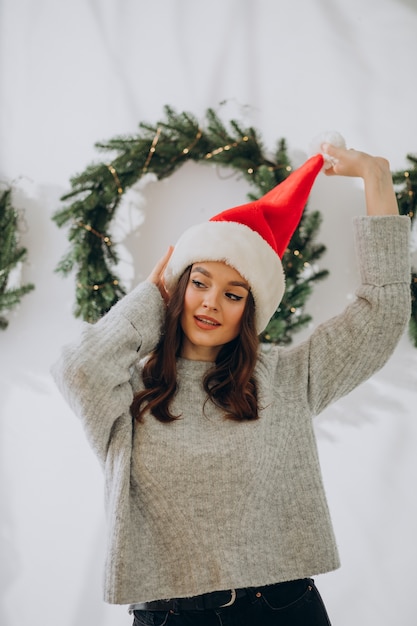 Free photo young woman wearing christmas hat on christmas