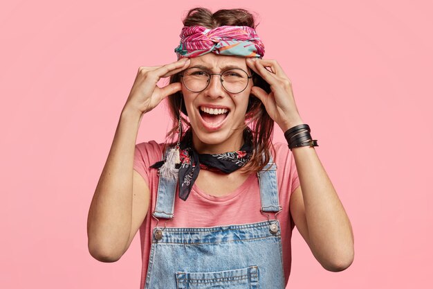 Young woman wearing colorful headband and denim overalls