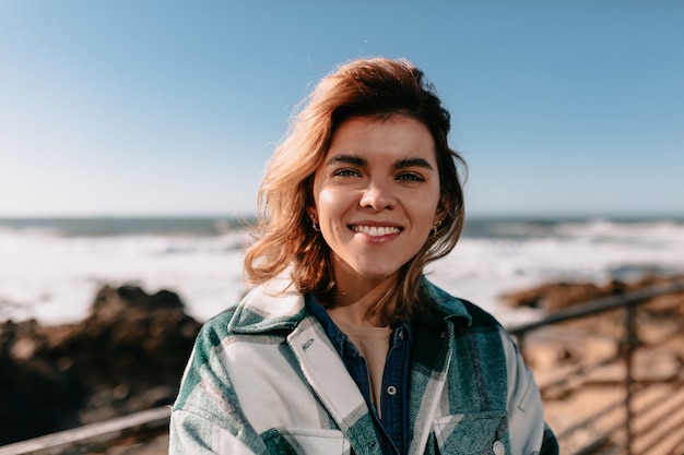 Young woman wearing denim shirt with smiling posing on beach