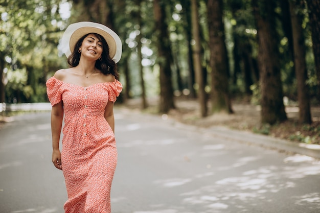 Foto gratuita giovane donna che indossa abiti e cappello a piedi nel parco